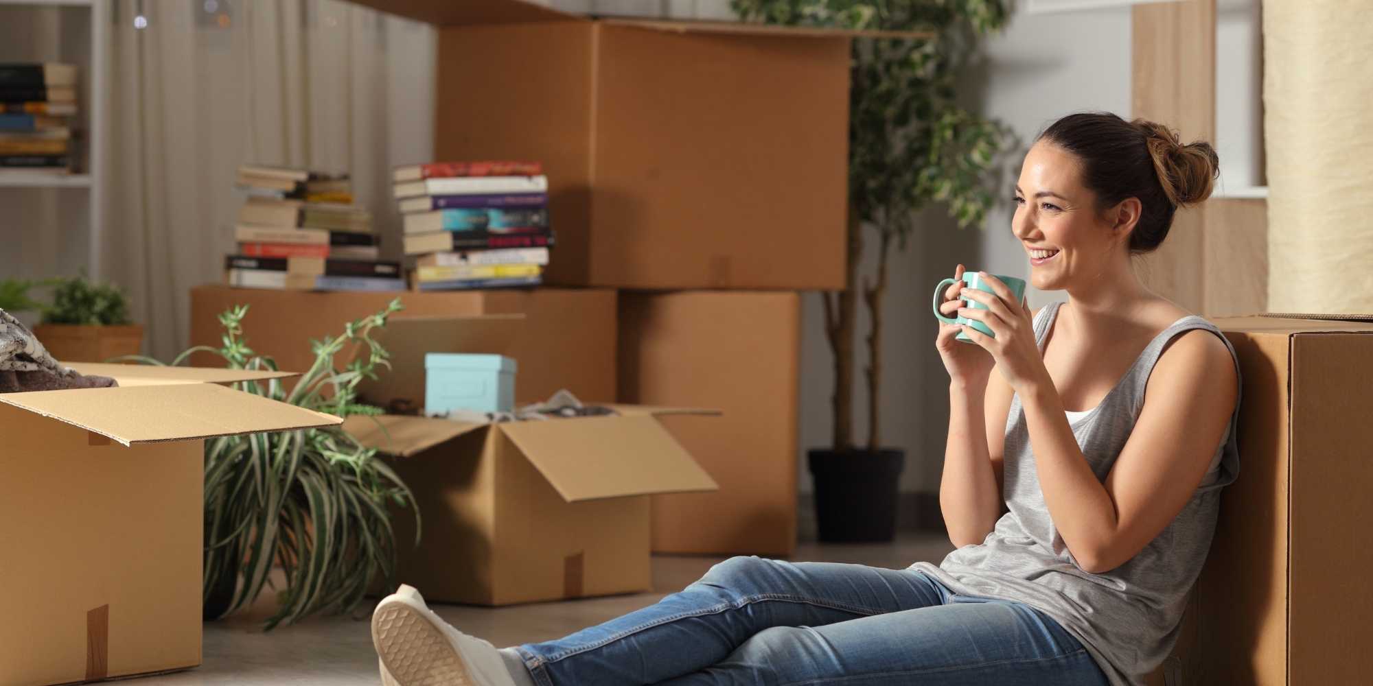 A happy women smiling enjoying a cup of coffee in her apartment after moving in symbolizing how moving can improve mental health.