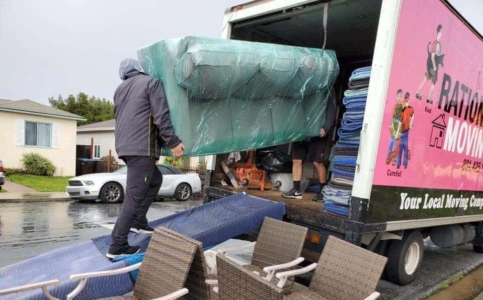 Professional movers carrying a couch up a ramp into a truck, showcasing local moving services.