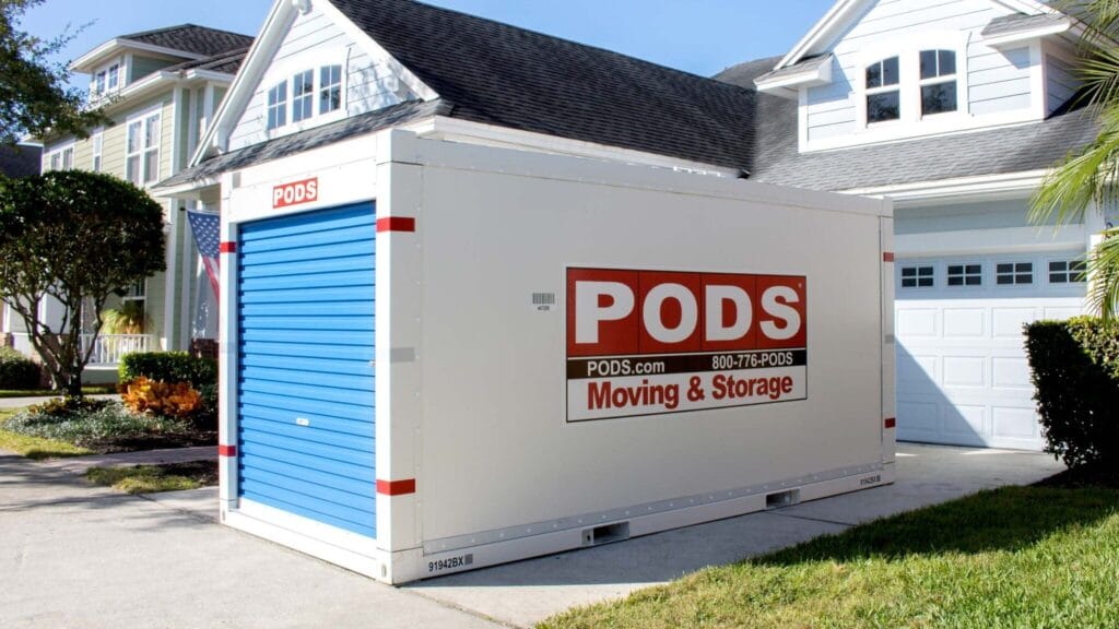 A portable storage container placed in the driveway of a suburban home, ready for moving or storage.