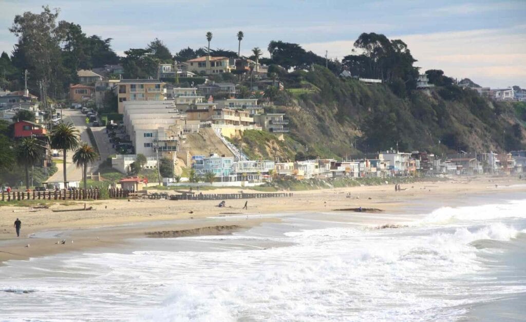 Scenic view of Aptos beach with ocean waves and coastal homes on the cliffs.