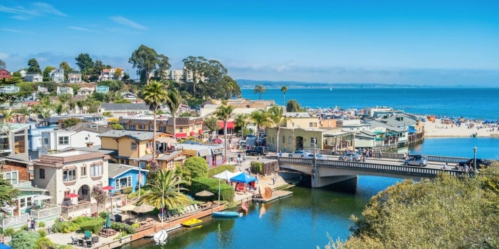 Colorful buildings and waterfront views in Capitola Village, with the beach and ocean in the background.