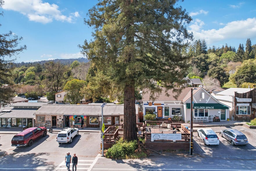 Downtown Felton, California, featuring small businesses, a towering redwood tree, and scenic greenery under a bright blue sky.