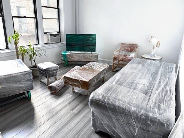 A living room with furniture wrapped in protective plastic, ready for a residential move.