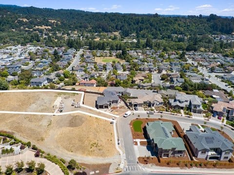 An aerial view of a residential neighborhood in Soquel, California, surrounded by greenery and rolling hills.