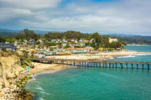 stunning view of Capitola Village with colorful houses, a scenic pier, and the vibrant beach along the coastline in Capitola, CA.