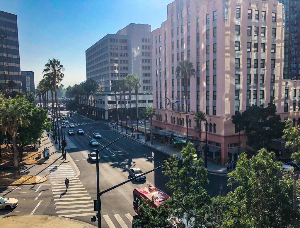 Downtown San Jose street view with historic buildings, palm trees, and cars, showcasing the vibrant atmosphere of the city.